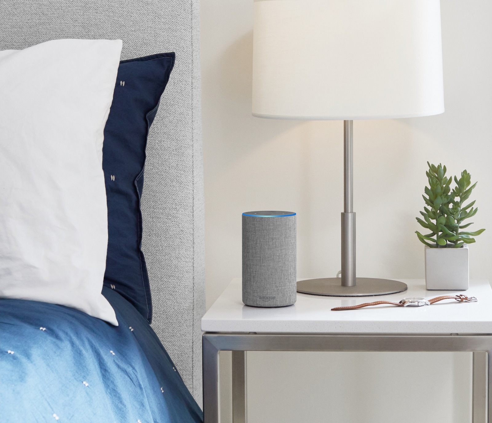 Alexa en una mesita de noche. Cama con edredón azul