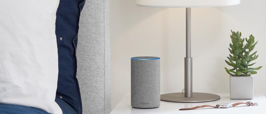 Alexa en una mesita de noche. Cama con edredón azul